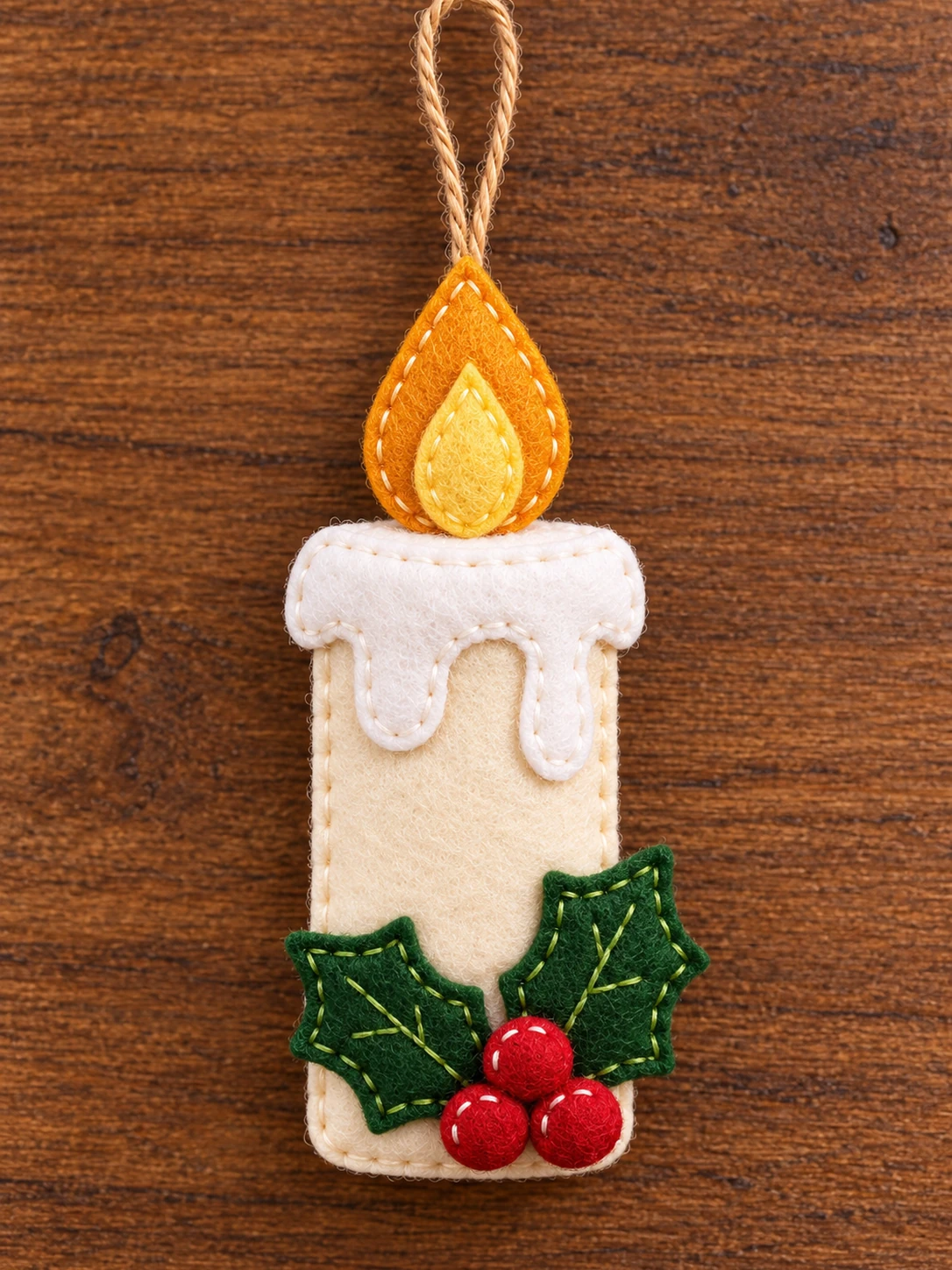Finished felt Christmas candle ornament with holly on warm wood