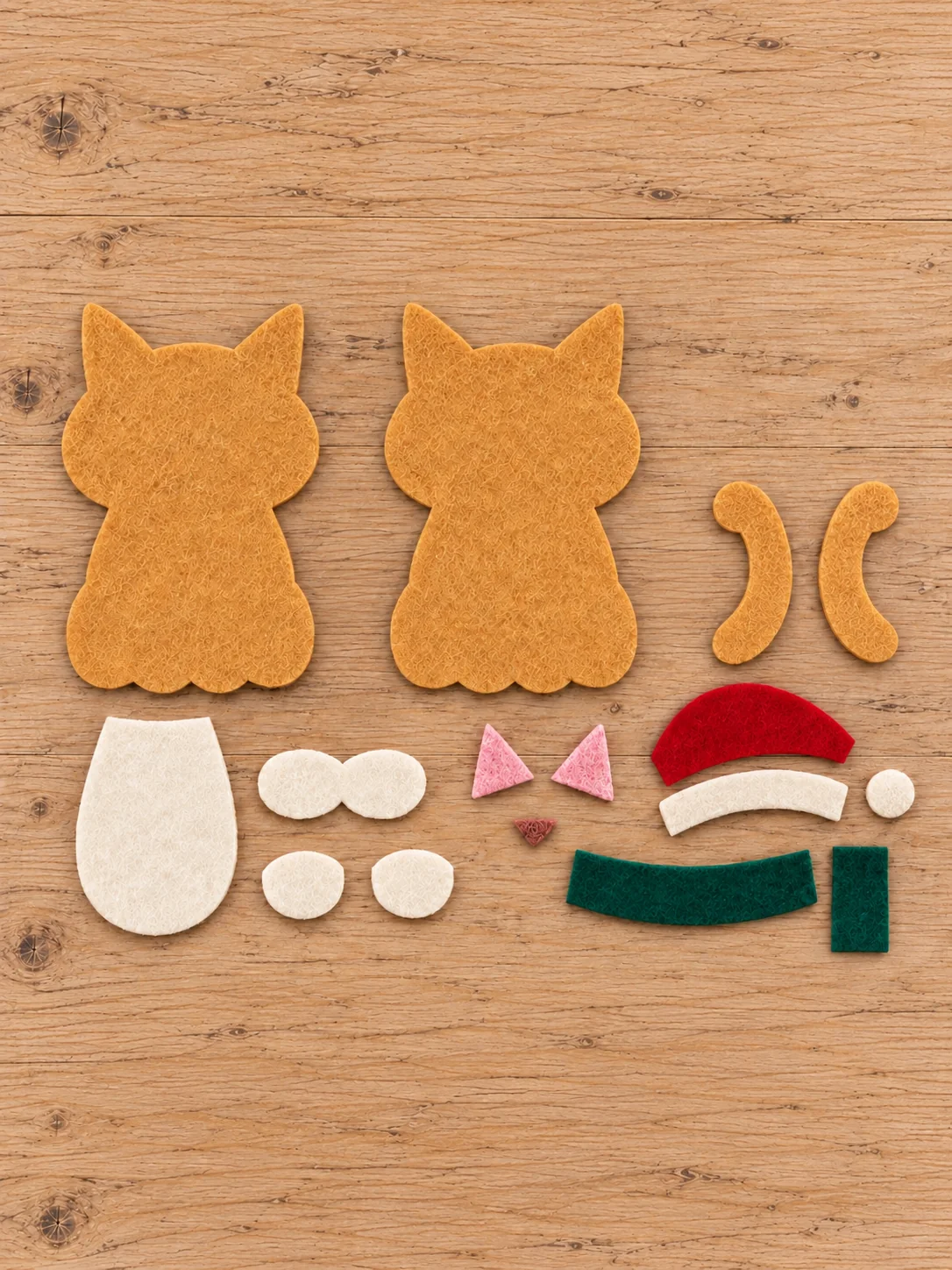 Cut golden tan cat bases and tail with ivory pink red and green felt appliqué pieces
