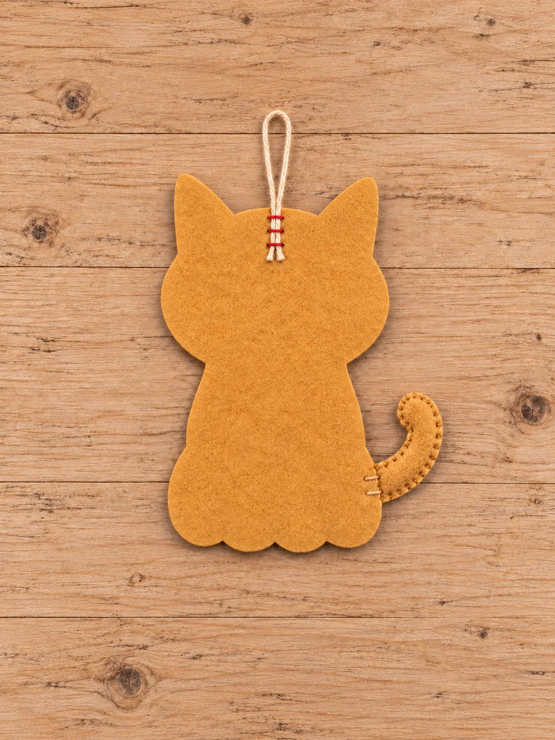 Back of felt cat showing attached curled tail and cotton cord hanging loop