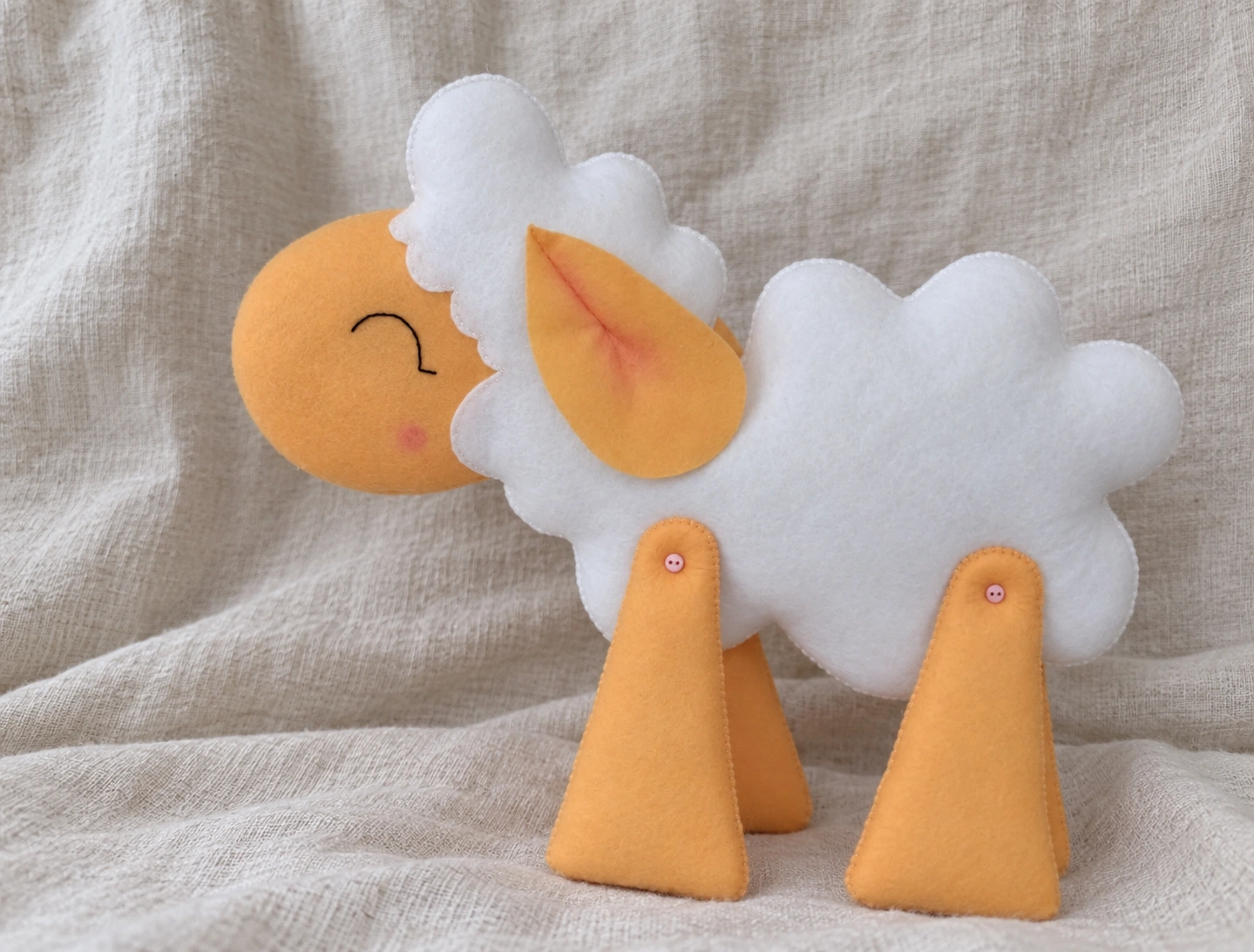 Completed white and beige felt sheep shown from one side