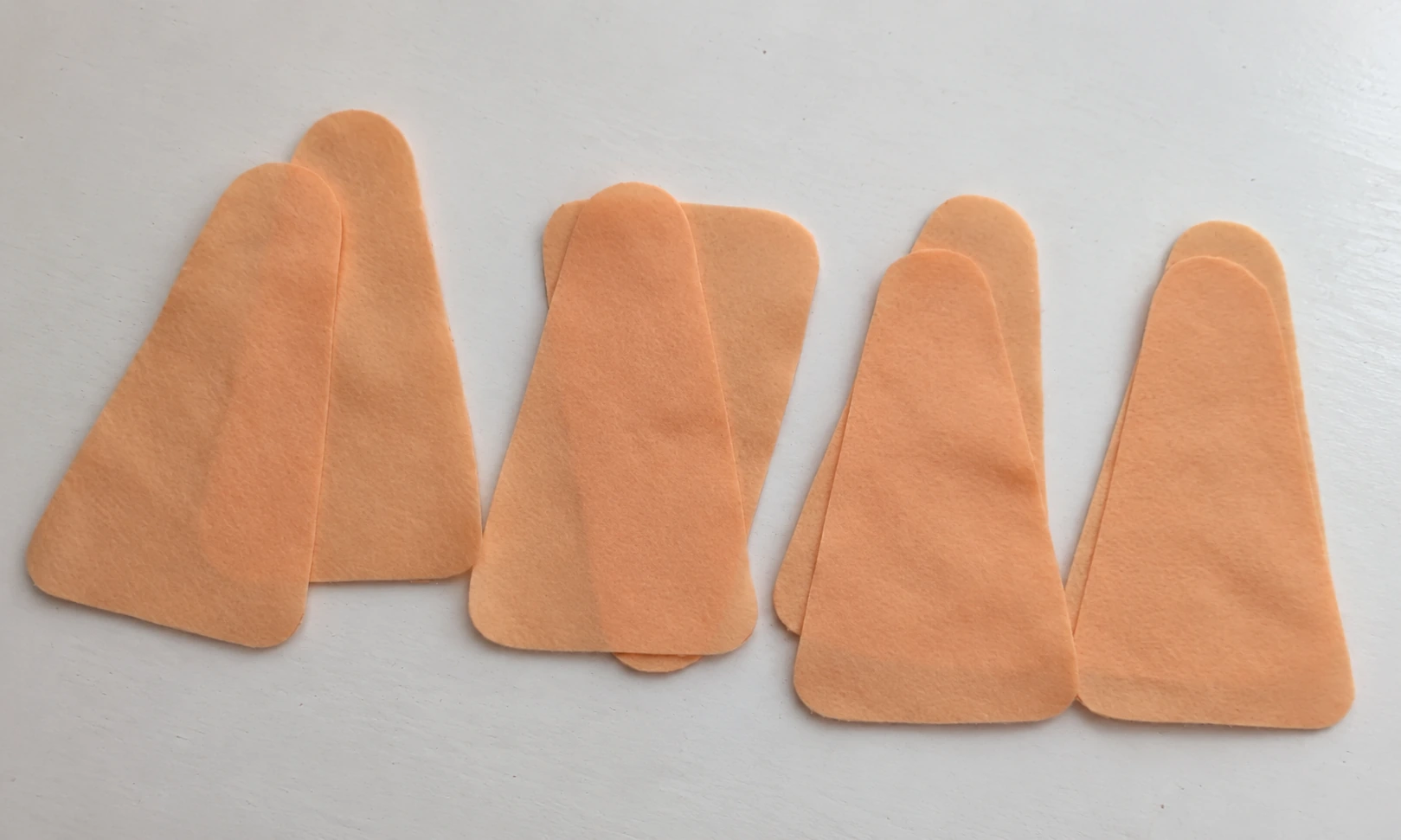Eight beige felt leg panels arranged on a white tabletop
