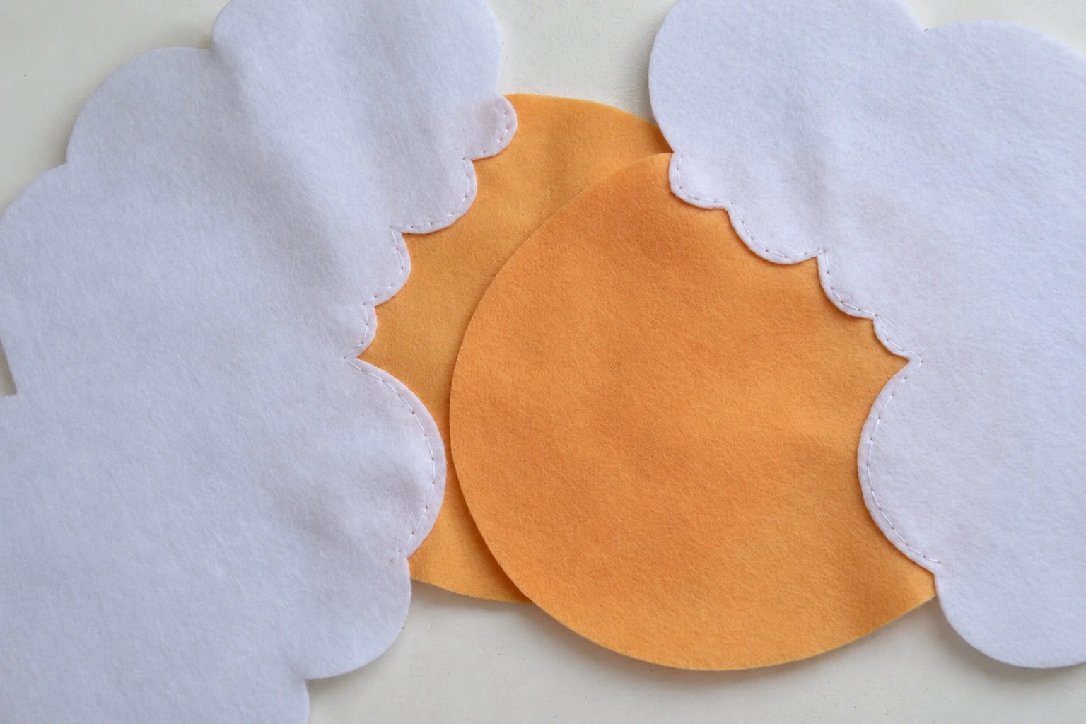 The second beige face sewn to its white felt body side