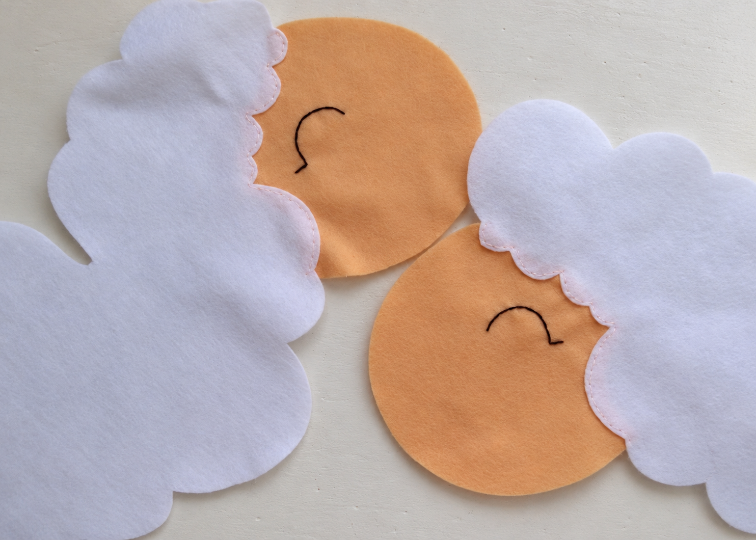 Two completed sheep faces with matching mirrored embroidered eyes