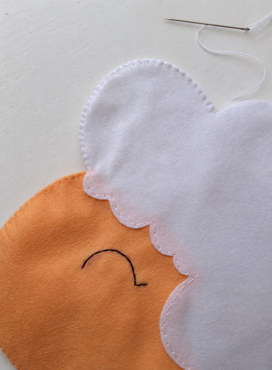 White stitching continuing around the top of the sheep head