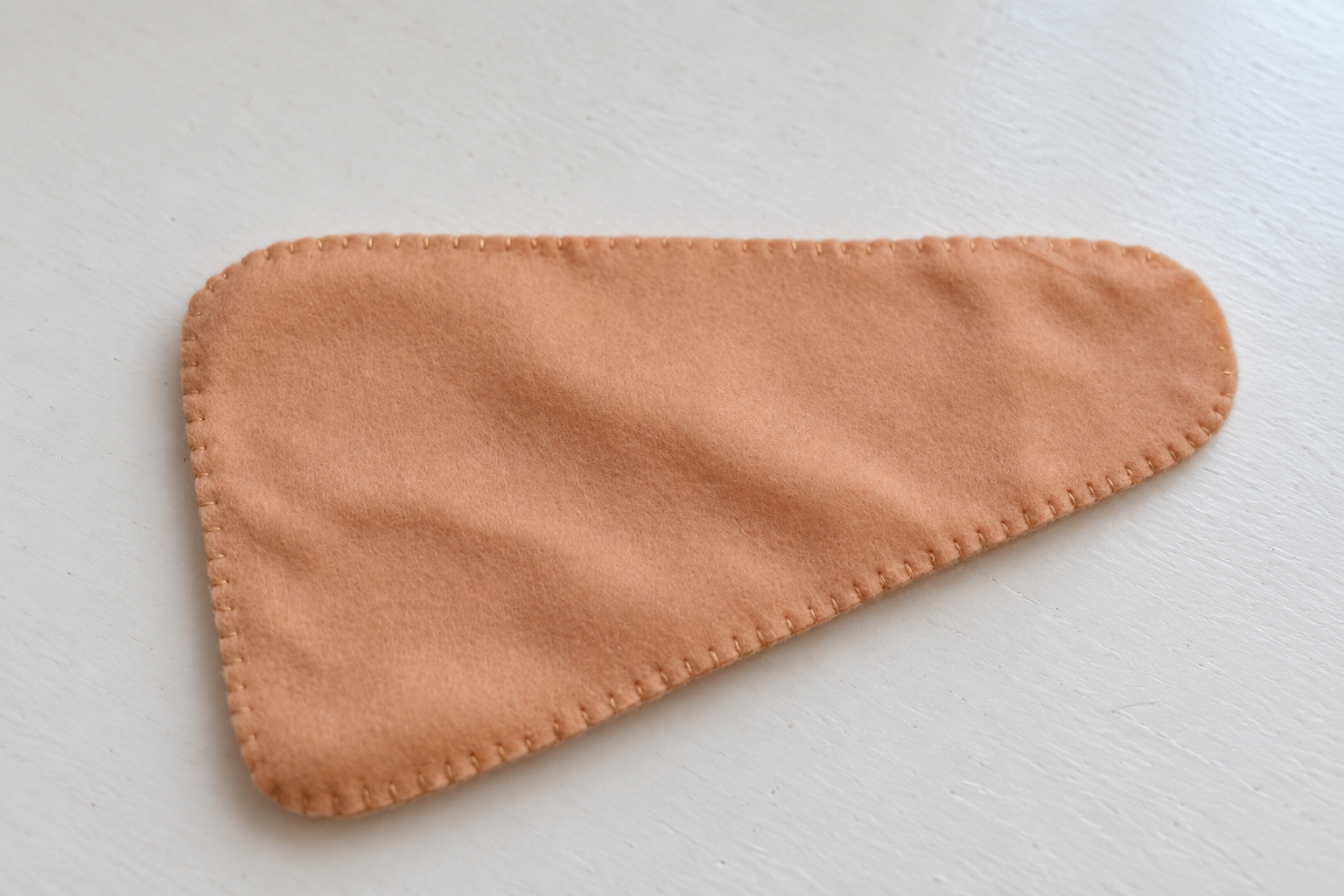 Beige blanket stitching around a paired felt leg