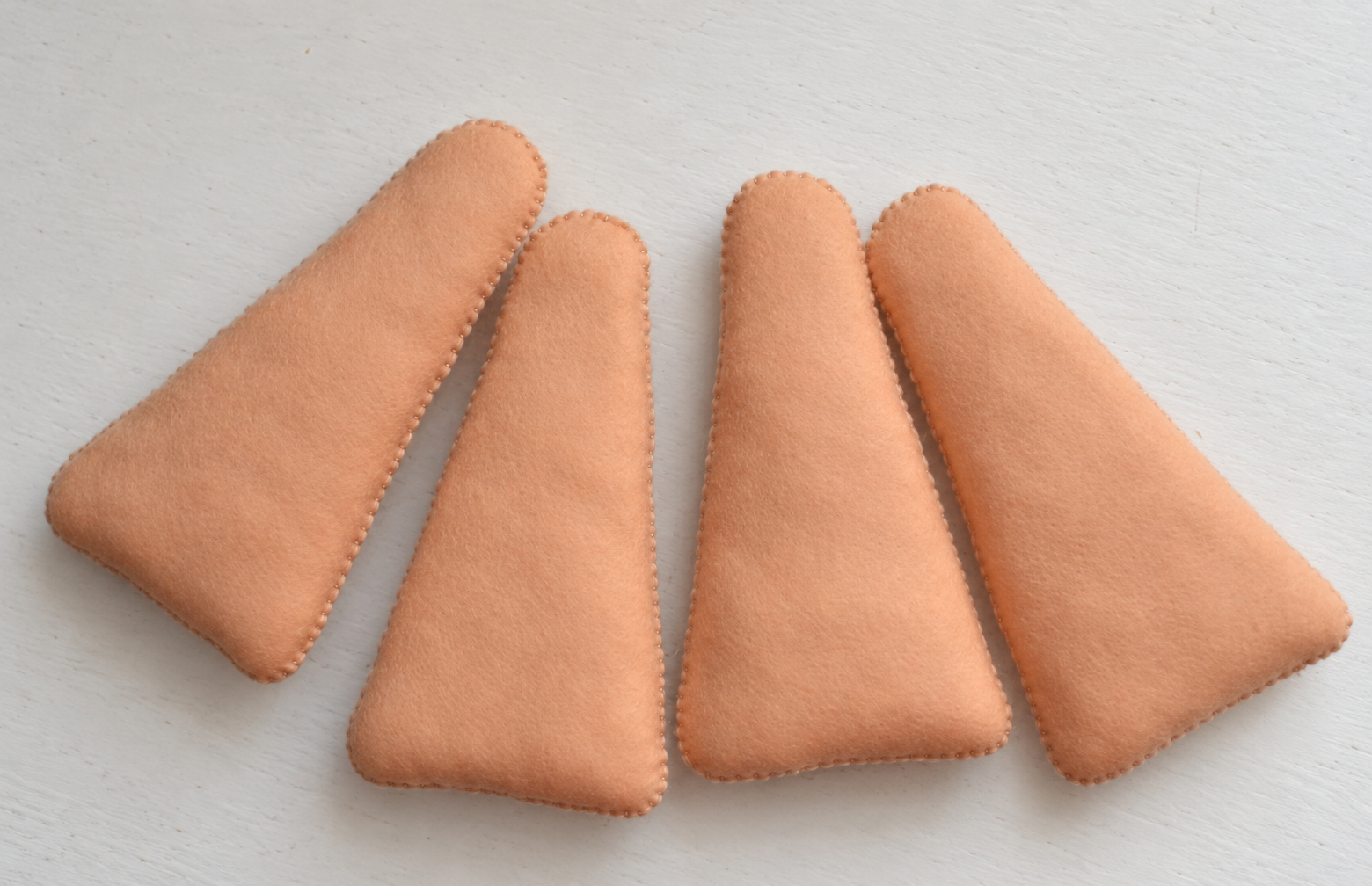 Four completed stuffed beige felt legs arranged together