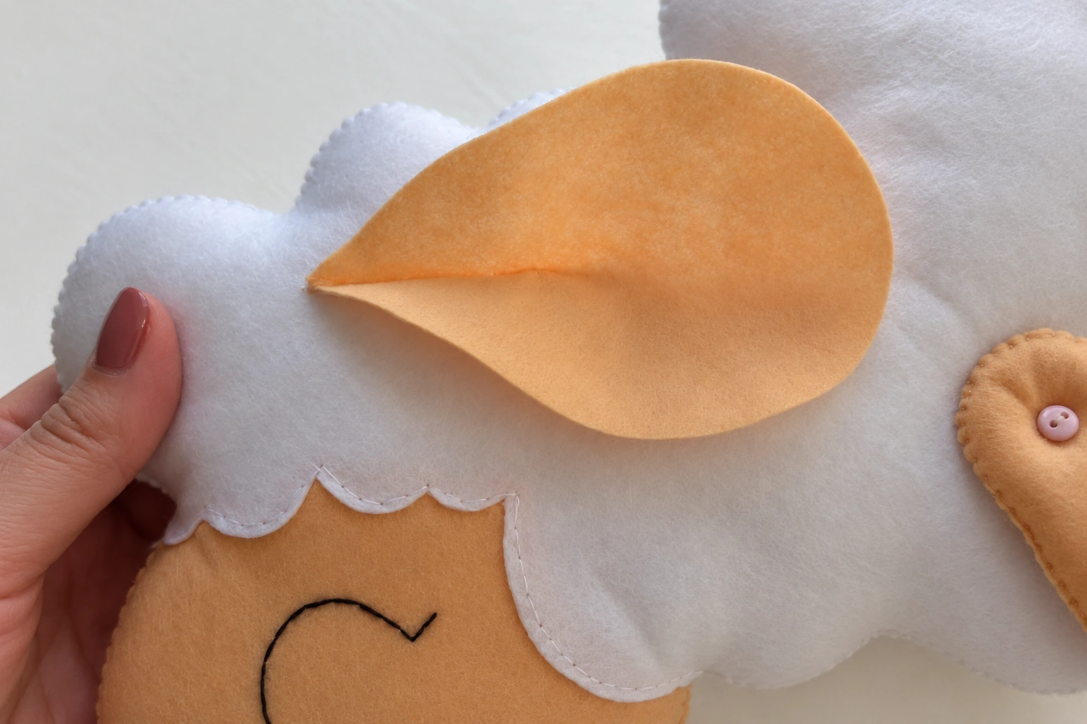 The folded beige ear positioned on the white sheep head