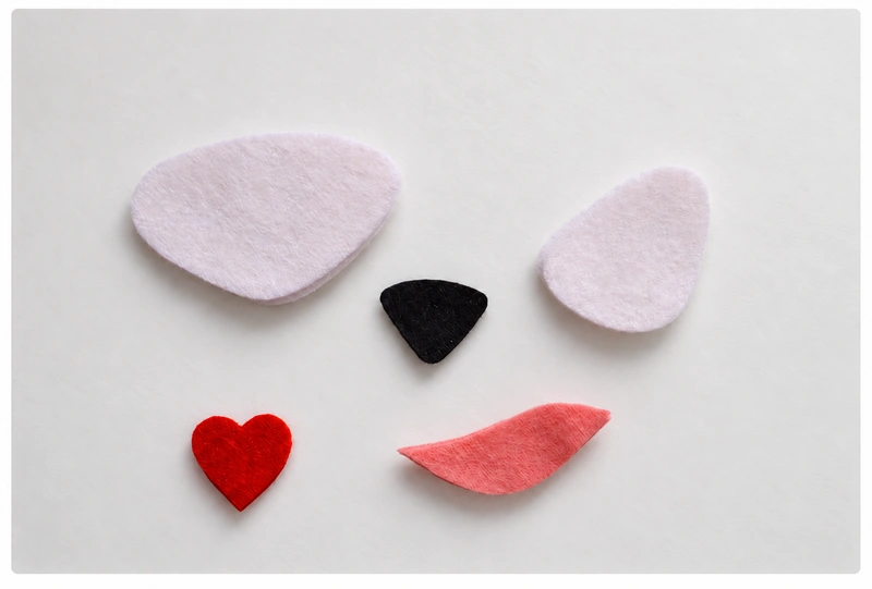 White muzzle and eye patches, a black nose, a red heart, and a pink inner ear