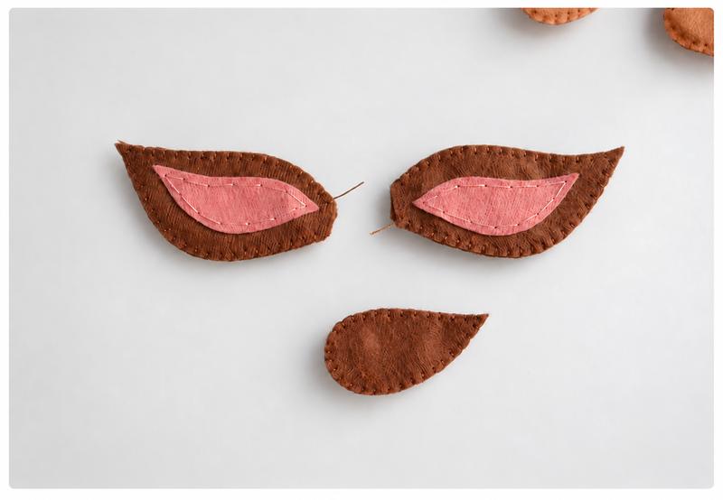 Completed felt ears and tail with brown blanket-stitched edges
