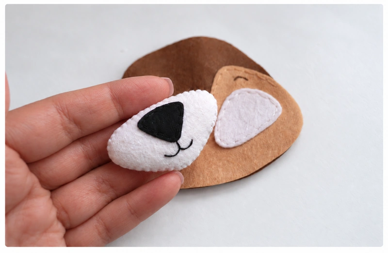 Padded white muzzle with an embroidered mouth and black nose
