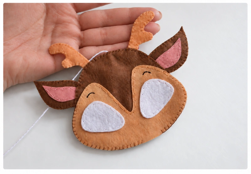 Head being blanket stitched with the ears, antlers, and hanging cord in place